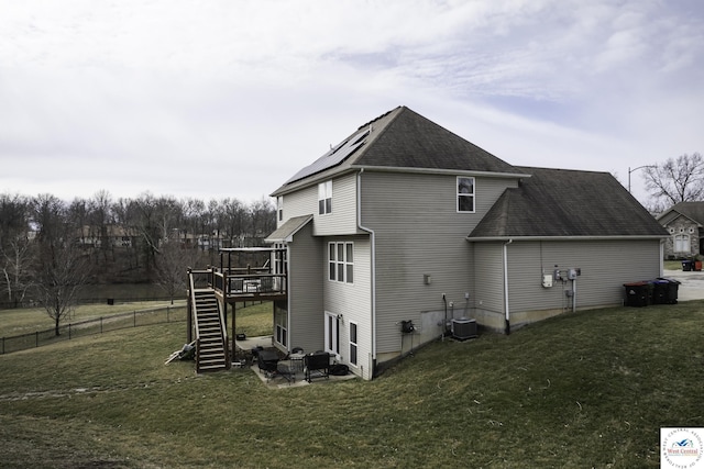 back of house with stairway, fence, a shingled roof, a deck, and a lawn