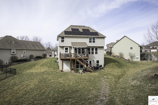 rear view of house featuring stairway, solar panels, a wooden deck, and a yard