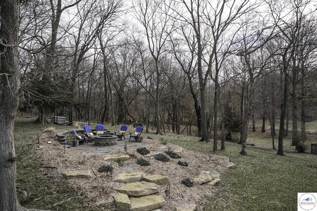 view of yard with a patio, a fire pit, and a forest view