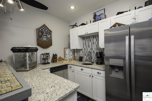 kitchen featuring light stone counters, a sink, white cabinets, appliances with stainless steel finishes, and backsplash