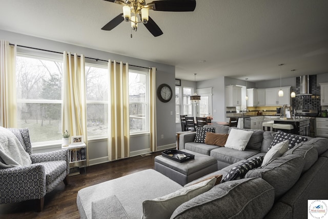 living area featuring dark wood finished floors, a textured ceiling, baseboards, and ceiling fan