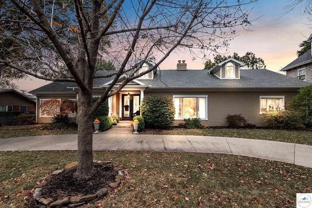 view of front of house featuring roof with shingles, a front lawn, and a chimney