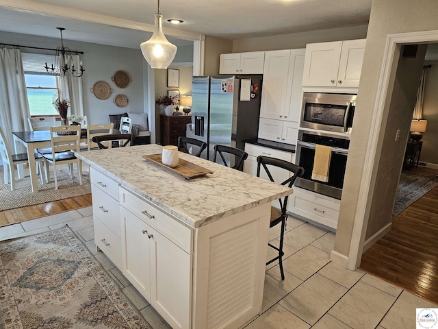 kitchen featuring stainless steel appliances, a breakfast bar, white cabinetry, and a kitchen island