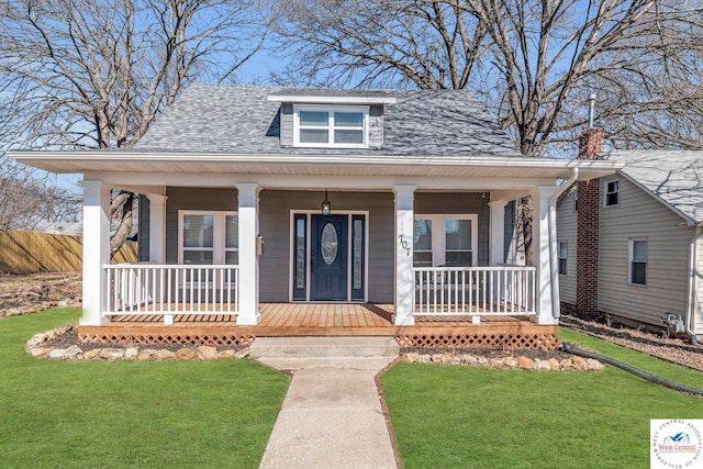 bungalow-style house with a porch, a shingled roof, and a front lawn