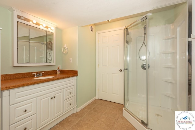 bathroom featuring tile patterned floors, a shower stall, vanity, and baseboards