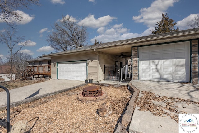 single story home featuring a fire pit, concrete driveway, and an attached garage