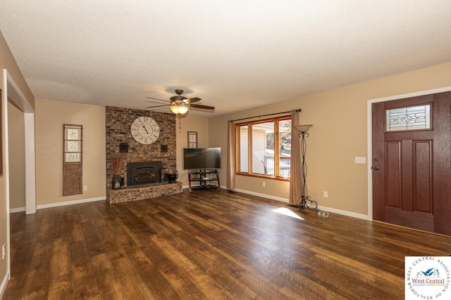 unfurnished living room featuring a textured ceiling, wood finished floors, baseboards, a brick fireplace, and ceiling fan