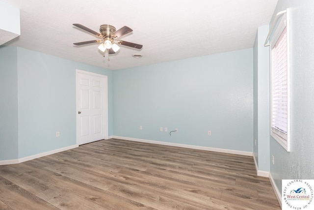 empty room with baseboards, wood finished floors, and a ceiling fan