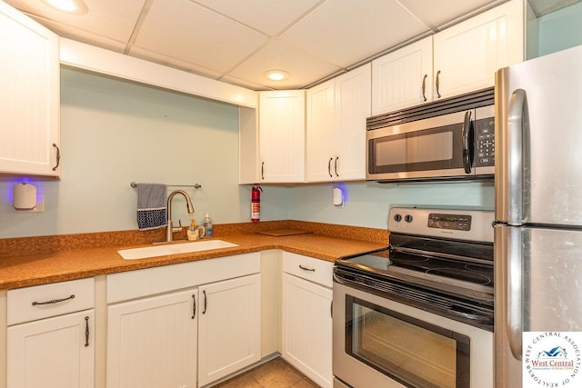 kitchen with a sink, a drop ceiling, recessed lighting, stainless steel appliances, and white cabinets