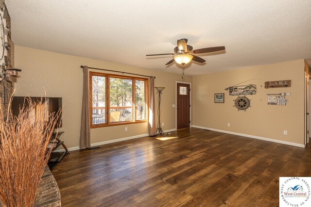 unfurnished living room with dark wood finished floors, a textured ceiling, and baseboards