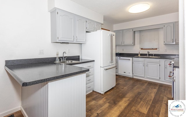 kitchen with white appliances, dark countertops, and a sink