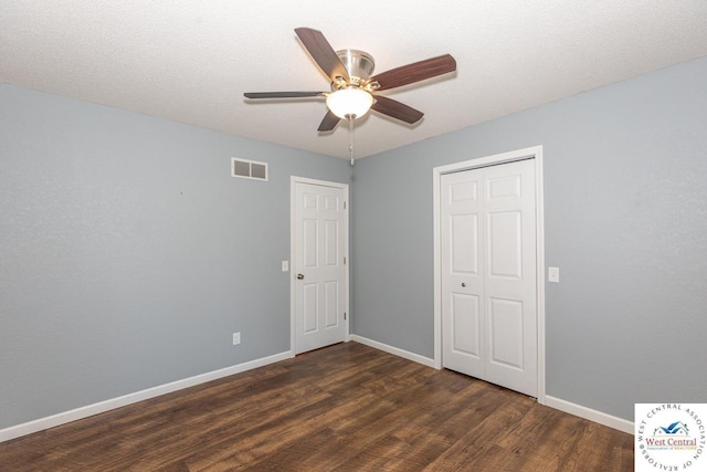 unfurnished bedroom featuring dark wood finished floors, baseboards, visible vents, and a ceiling fan