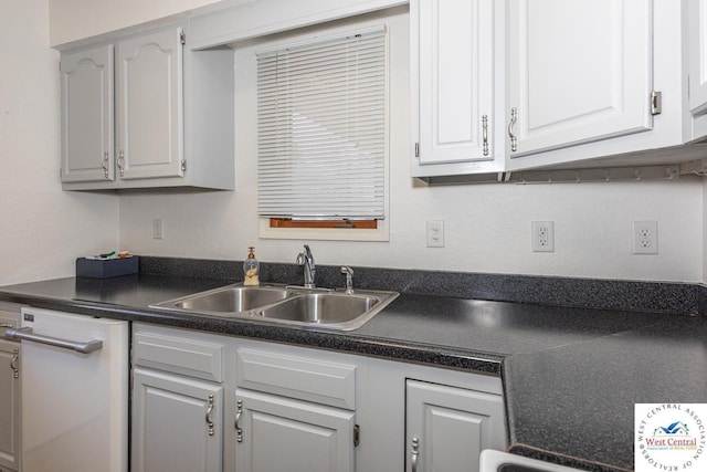 kitchen with dishwasher, dark countertops, white cabinetry, and a sink