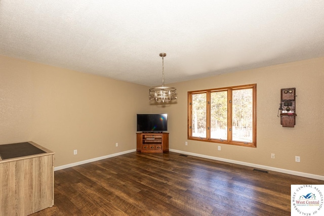 unfurnished living room featuring dark wood finished floors, visible vents, a notable chandelier, and baseboards