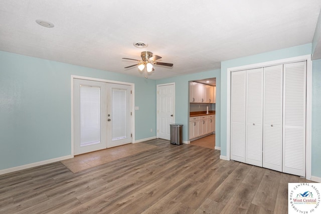 unfurnished bedroom with visible vents, baseboards, light wood-style floors, ensuite bathroom, and two closets