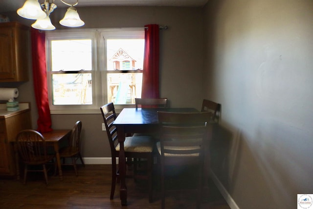 dining space with baseboards, an inviting chandelier, and wood finished floors