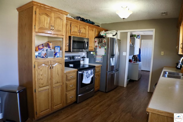 kitchen with dark wood-style floors, a sink, light countertops, appliances with stainless steel finishes, and a textured ceiling