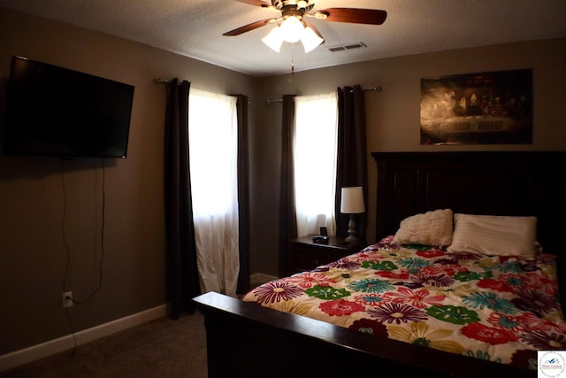 carpeted bedroom with visible vents, baseboards, a textured ceiling, and ceiling fan