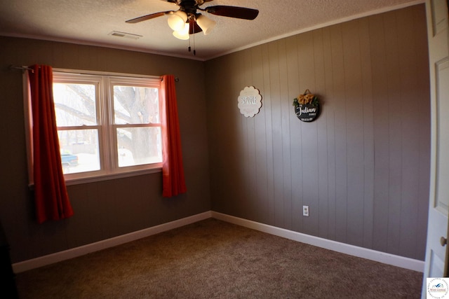 unfurnished room featuring visible vents, a textured ceiling, dark carpet, and a ceiling fan