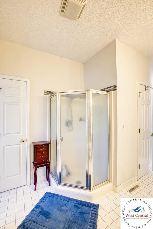 full bathroom featuring a stall shower, tile patterned flooring, visible vents, and a textured ceiling