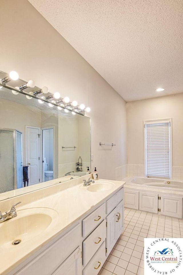 full bathroom featuring a garden tub, a textured ceiling, tile patterned flooring, and a sink