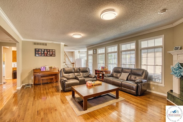 living area featuring stairway, visible vents, a fireplace with raised hearth, and wood finished floors