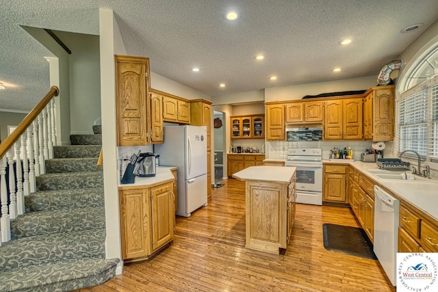 kitchen featuring a center island, white appliances, light countertops, and a sink