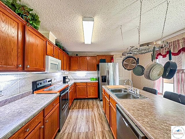 kitchen featuring appliances with stainless steel finishes, light countertops, a sink, and wood finished floors