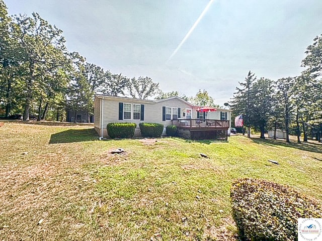 view of front facade with a wooden deck and a front yard