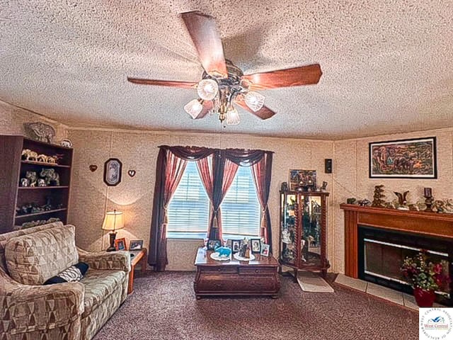 carpeted living area with a fireplace with flush hearth, a textured ceiling, and a ceiling fan