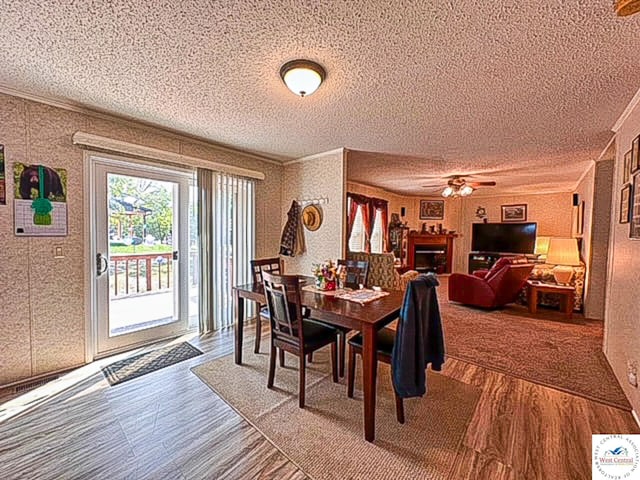 dining room featuring a textured ceiling, a fireplace, wood finished floors, and crown molding