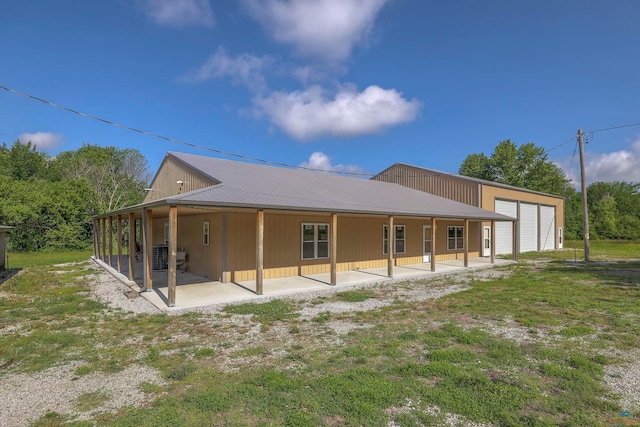 rear view of property featuring a yard, a patio area, metal roof, and a garage