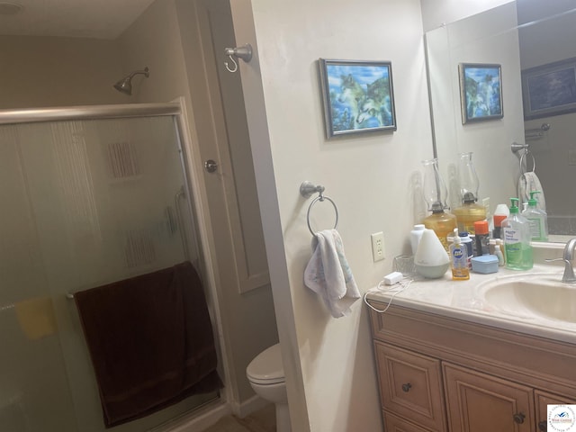 bathroom featuring vanity, a shower stall, and toilet