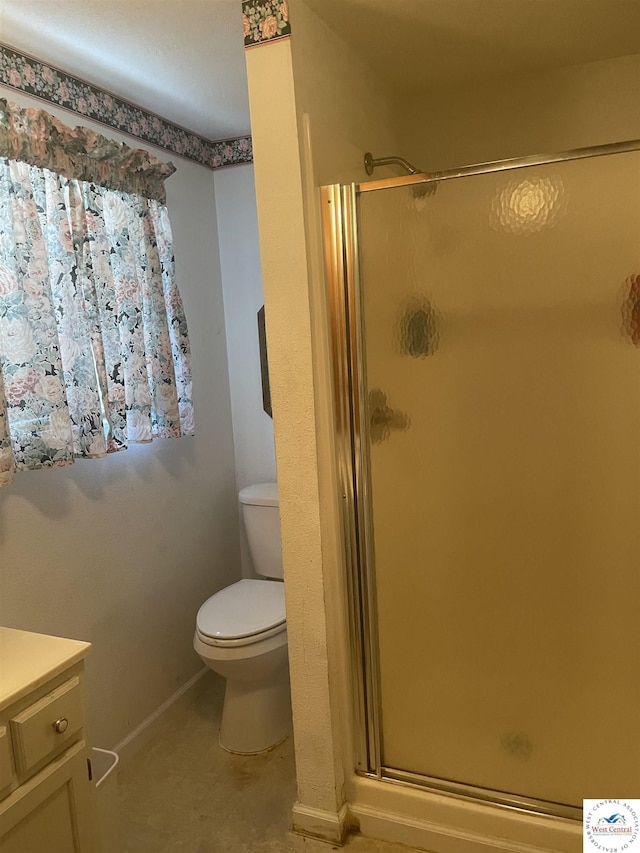 bathroom featuring baseboards, vanity, toilet, and a shower stall