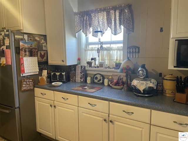 kitchen featuring dark countertops, white cabinets, and freestanding refrigerator