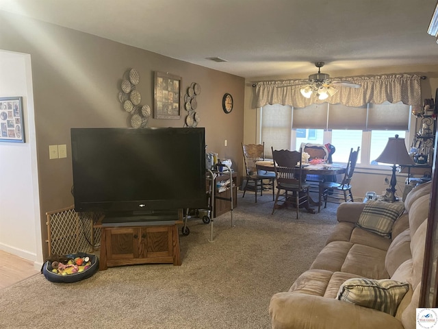 living area featuring baseboards, carpet, visible vents, and ceiling fan