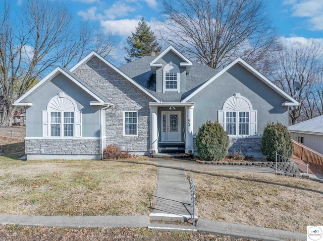 view of front of property featuring stone siding, a shingled roof, a front lawn, and stucco siding