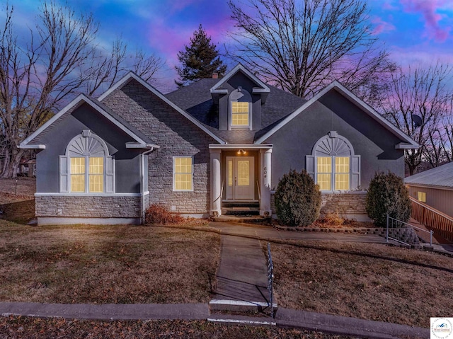 view of front of property with entry steps, stone siding, roof with shingles, and stucco siding