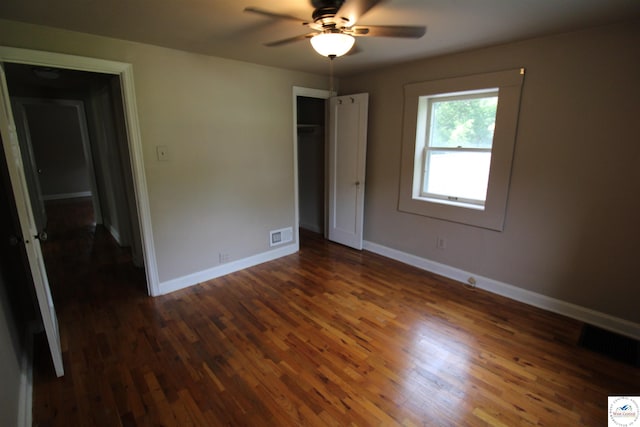 unfurnished bedroom with dark wood-type flooring, visible vents, and baseboards