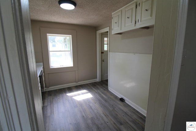 interior space featuring dark wood-style floors, baseboards, and a textured ceiling