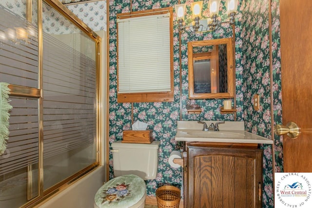 bathroom with enclosed tub / shower combo, vanity, toilet, and wallpapered walls