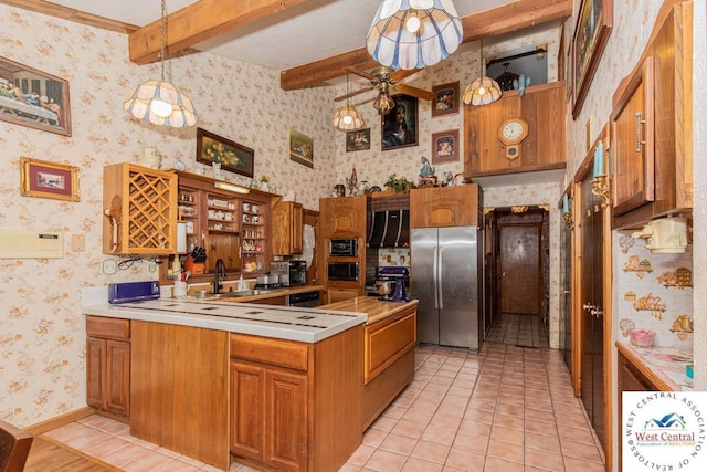 kitchen featuring brown cabinets, decorative light fixtures, light countertops, freestanding refrigerator, and wallpapered walls