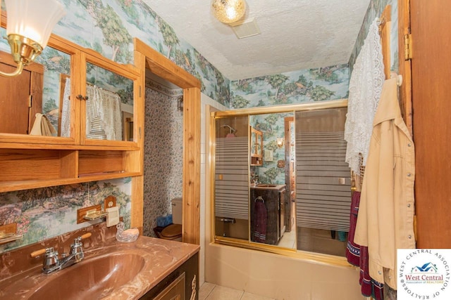 bathroom featuring wallpapered walls, enclosed tub / shower combo, tile patterned flooring, a textured ceiling, and vanity