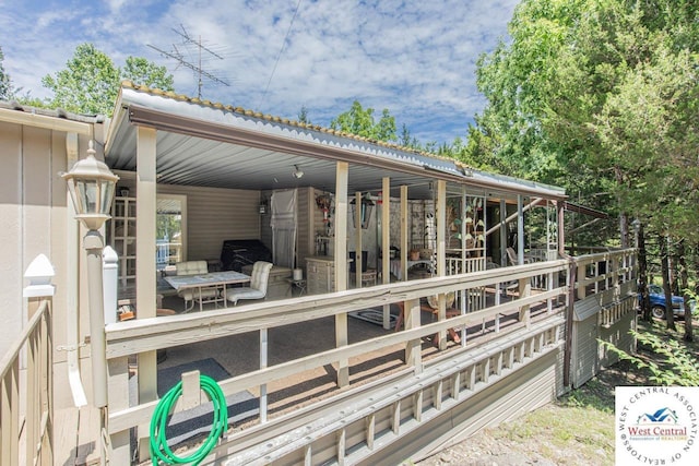 deck featuring area for grilling, an outdoor structure, and an exterior structure