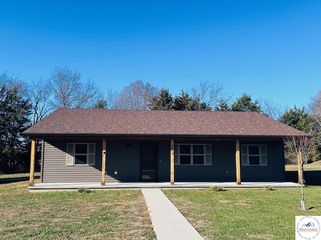 ranch-style home featuring a front lawn and roof with shingles