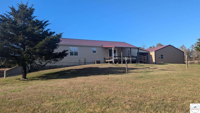 rear view of property featuring metal roof, a lawn, and a wooden deck