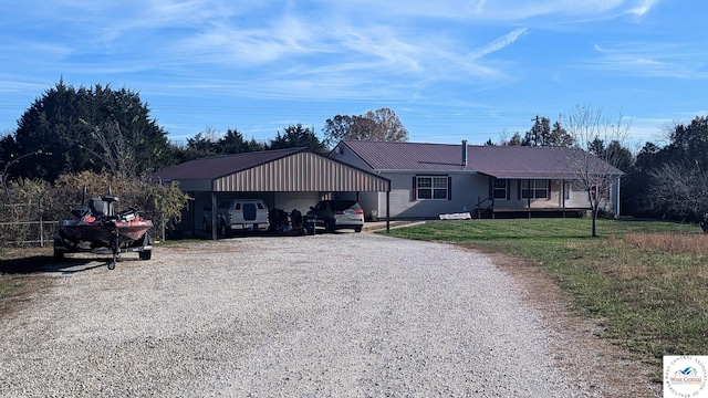 ranch-style house featuring metal roof, a carport, a front yard, and driveway