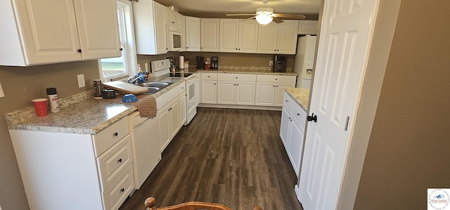 kitchen featuring white appliances, a sink, white cabinetry, a ceiling fan, and dark wood-style floors