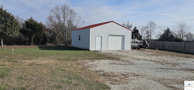 detached garage featuring fence and driveway