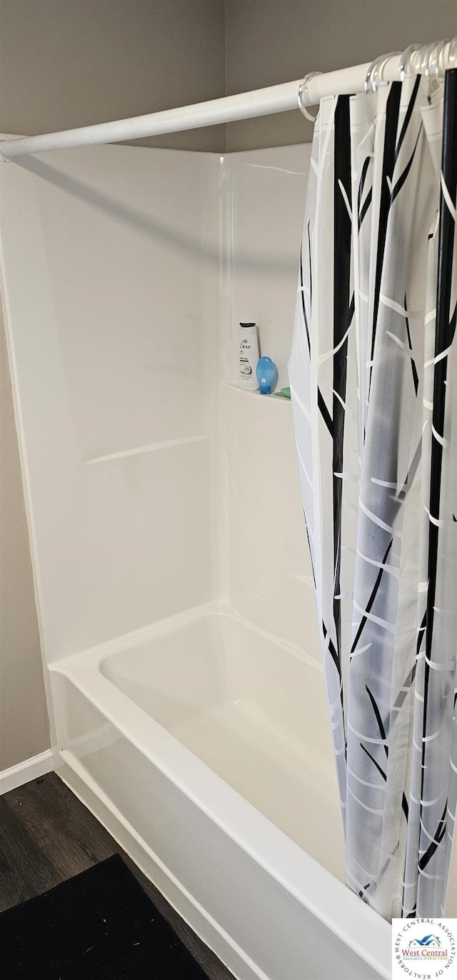 full bath featuring shower / bath combination with curtain, wood finished floors, and baseboards